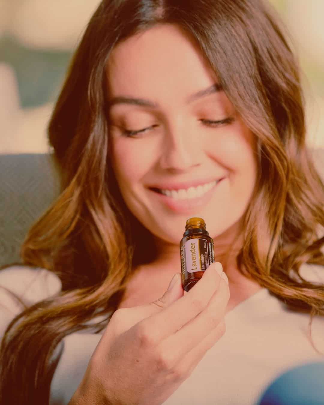 Frau lächelt, hält doterra Lavendel Öl in der Hand