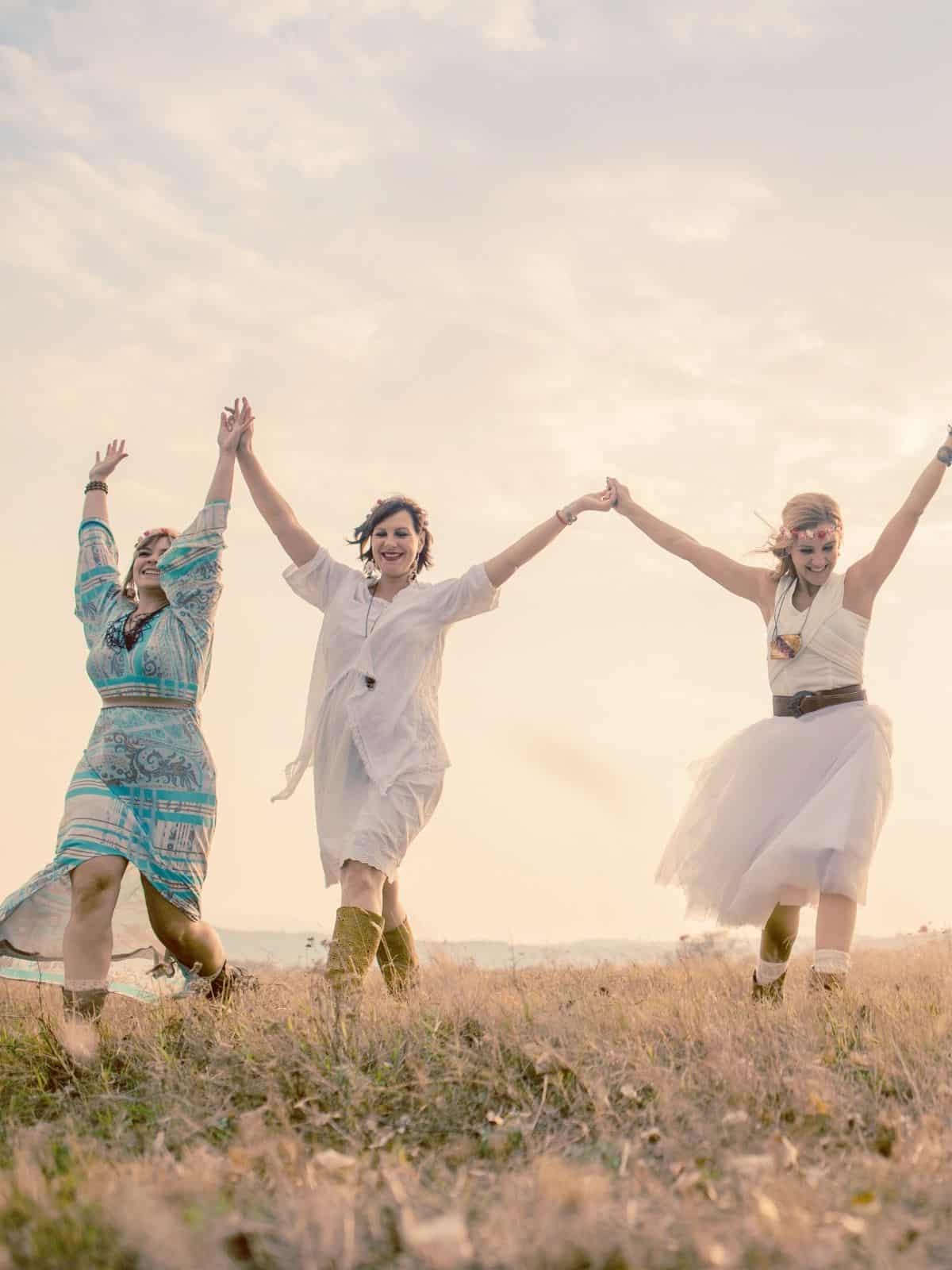 3 Frauen halten zusammen die Arme hoch.